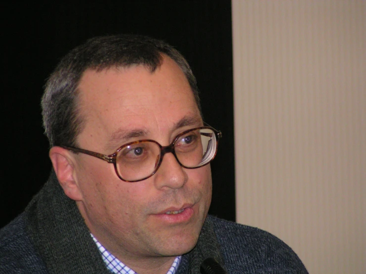 a man is speaking with microphone on black and white background