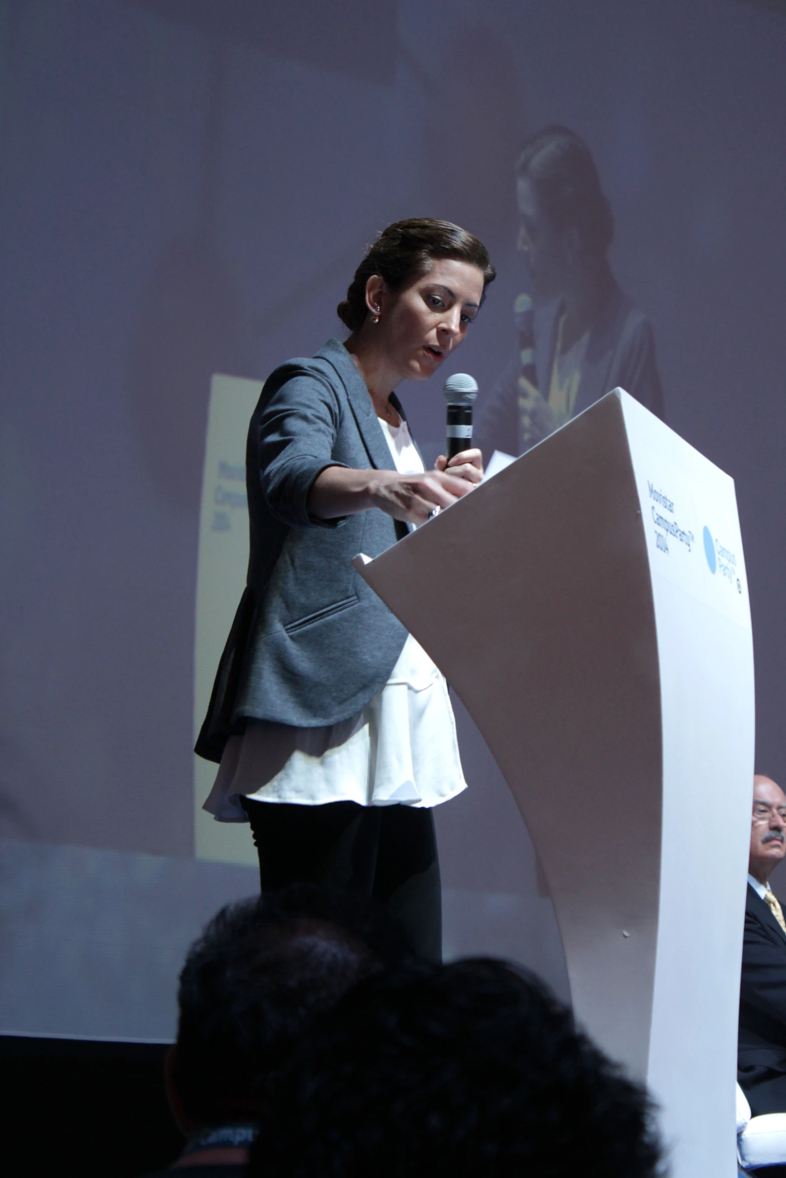 a woman in gray jacket speaking at podium