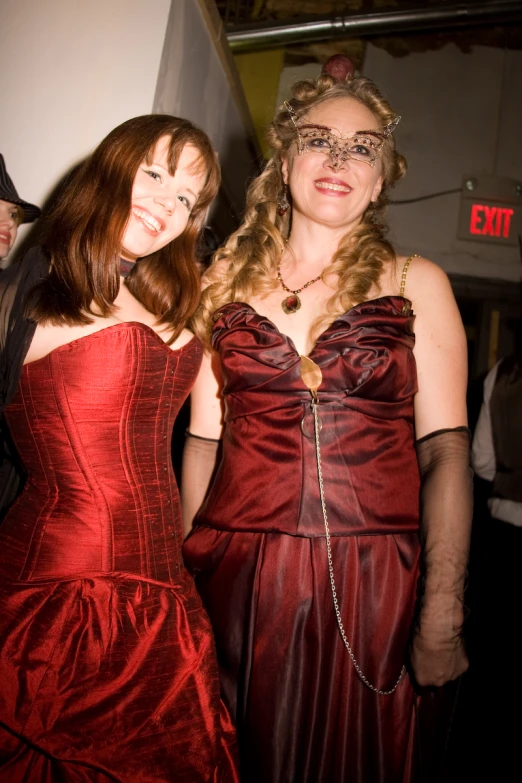 two women dressed in evening wear smiling at the camera