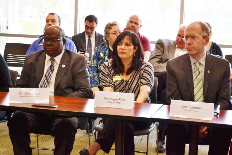 a group of people in suits are sitting at a table