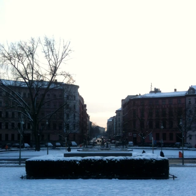 a snowy park and fountain in the middle of the street