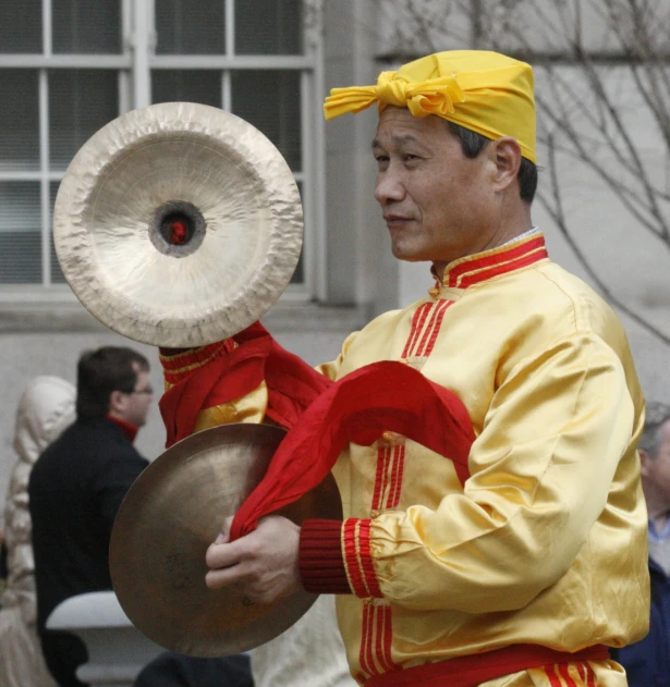 a man in yellow is holding a large metal disk