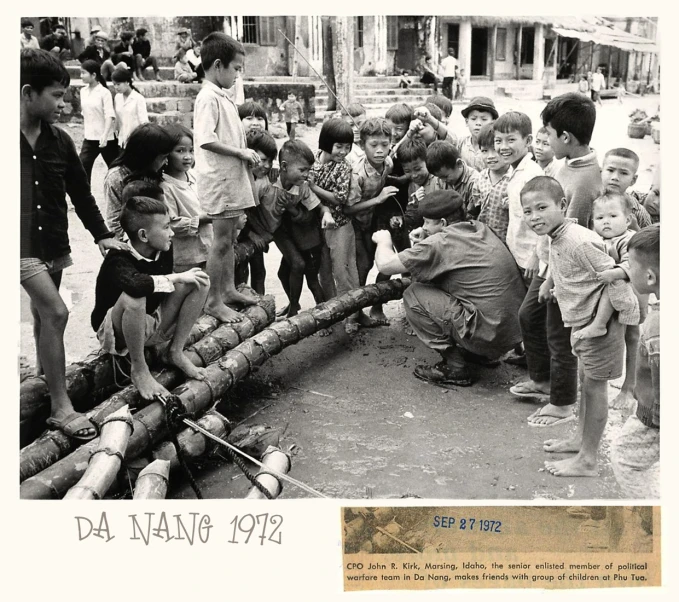 children stand around an old water source with pipes and a sign that reads da nang, 1917