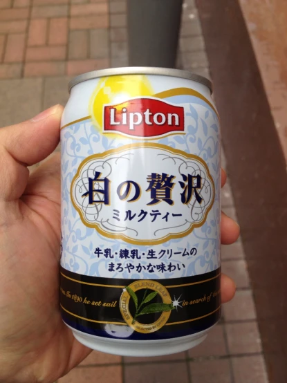 a hand holding a can of lipton tea