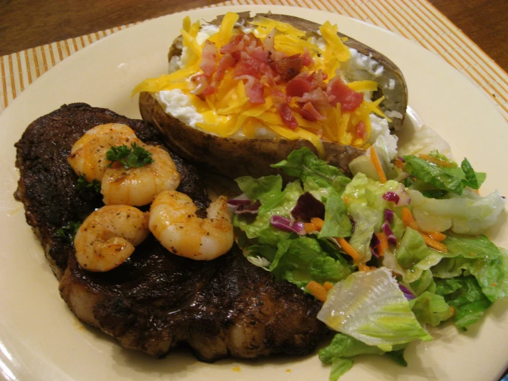 steak, salad, and baked potato are served on a plate