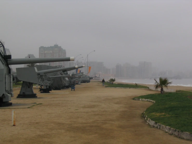 some tanks line a path along a large body of water