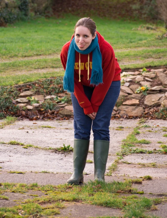 a woman in rain boots standing by some water