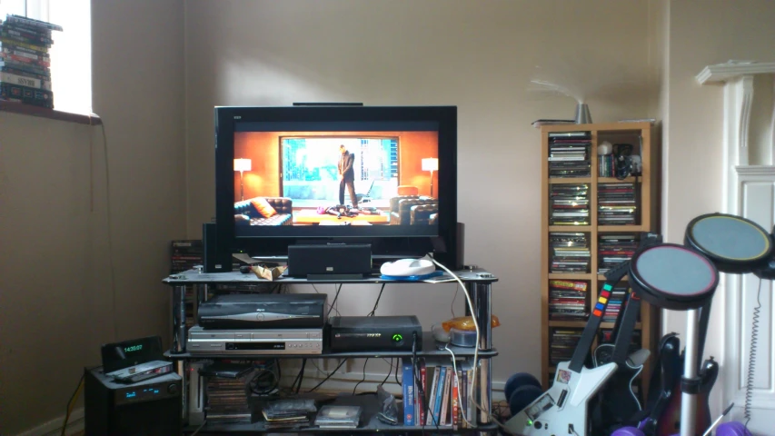 the tv is on above a shelf full of musical equipment