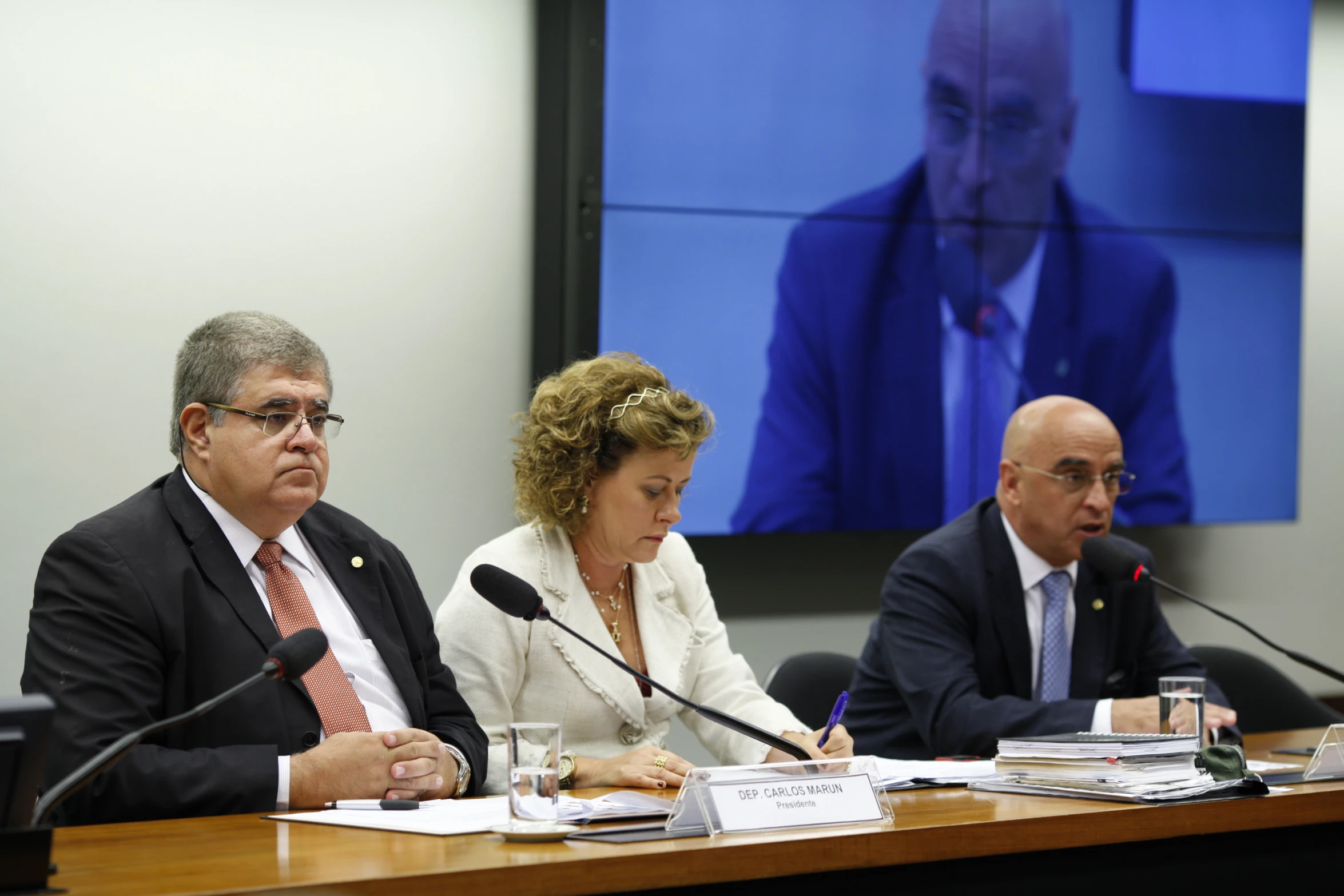 three people are seated at a table with microphones