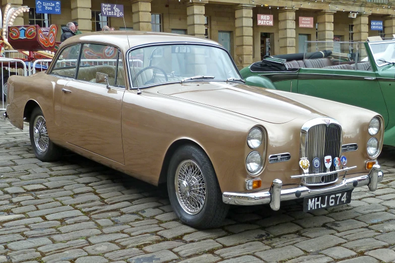 a brown car sitting in front of another green car