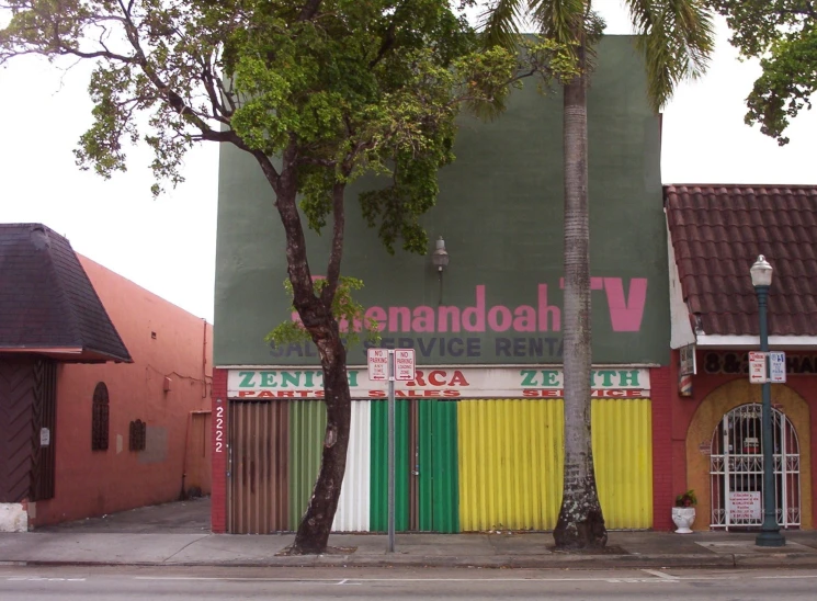 an empty street with a colorful shopfront and palm trees