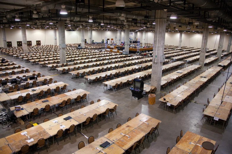 tables with wooden desks are lined up in a large building
