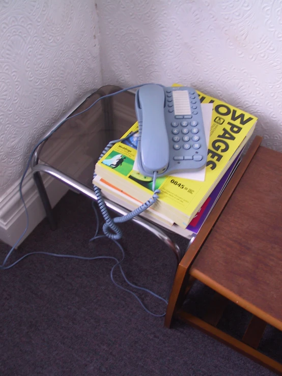 a telephone on top of books on a glass desk