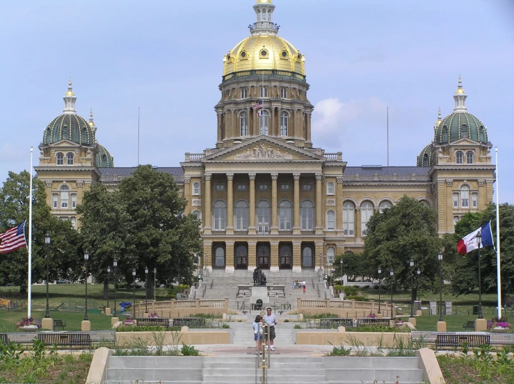 two people are sitting on a park and in front of a historic building