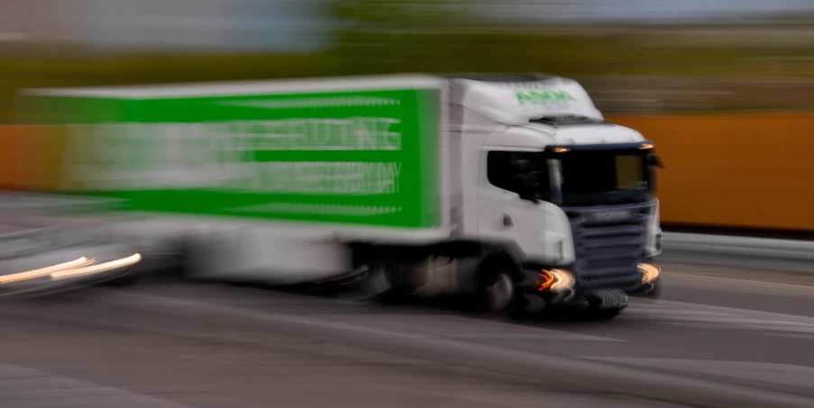a blurry po of a green semi truck driving down a road