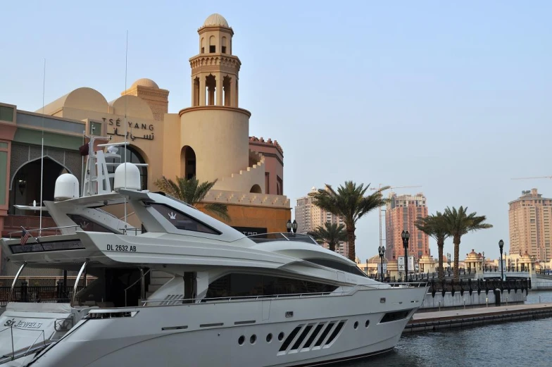 a white yacht sitting on the side of a river next to buildings