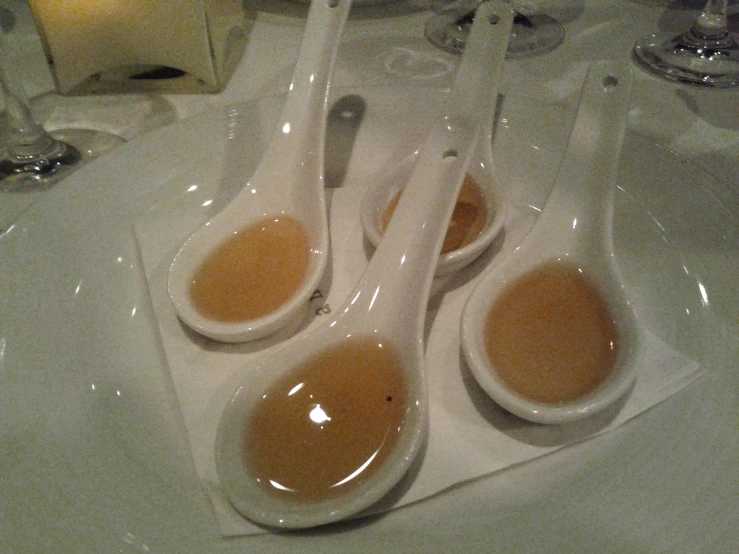 spoons are covered with sauces in a white ceramic bowl