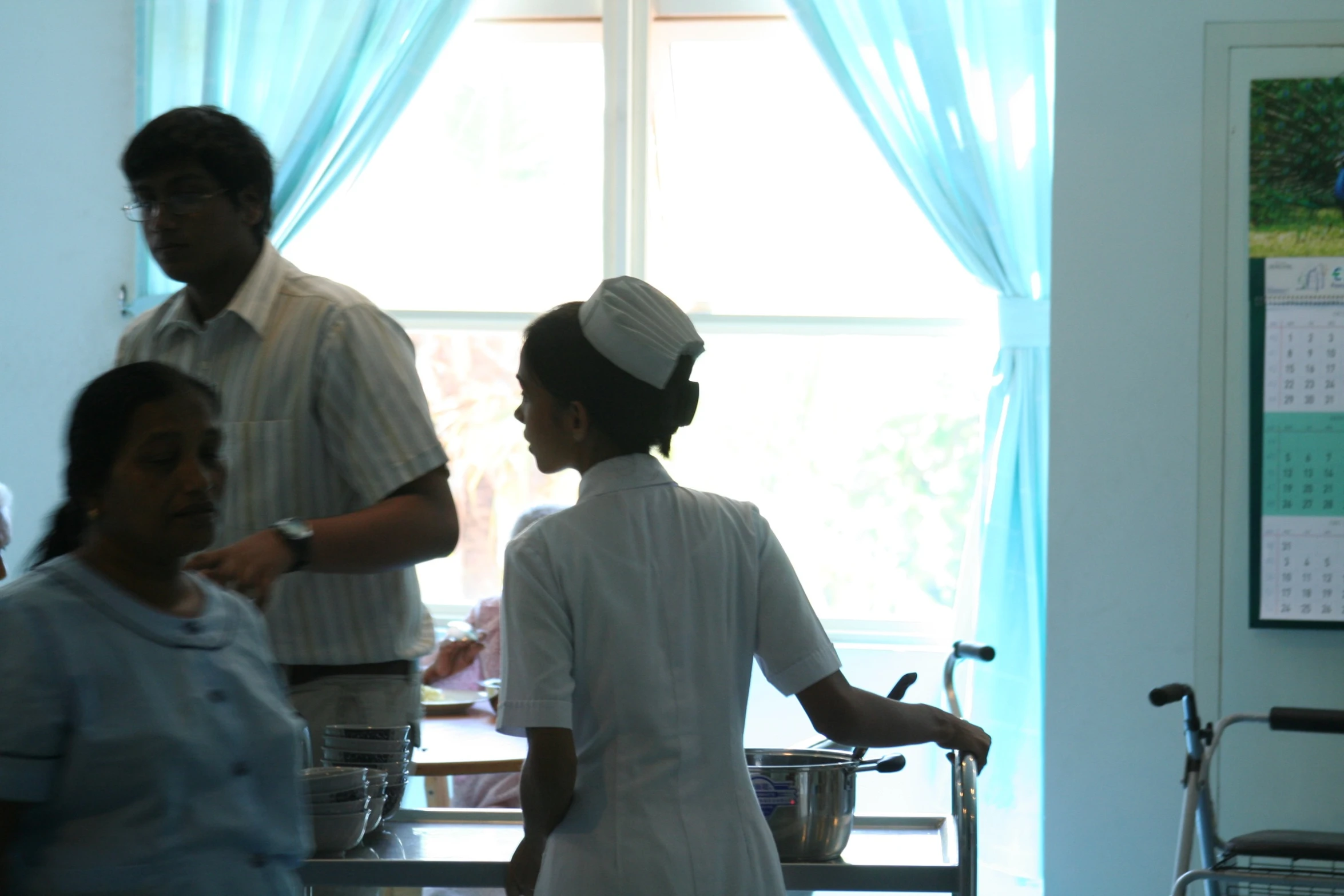 an asian man and a female nurse are standing by a window