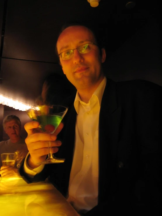 a man sitting at a table holding up a wine glass