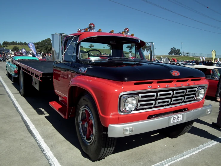 red flatbed truck parked in a lot next to a man