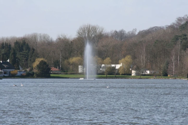 a water fountain spewing out water into the air near a lake