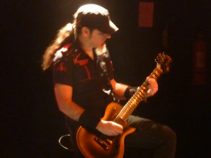 a man sitting in front of a laptop computer playing a guitar