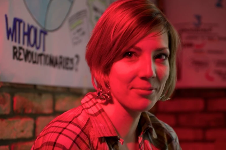 a woman in plaid shirt sitting in front of a brick wall