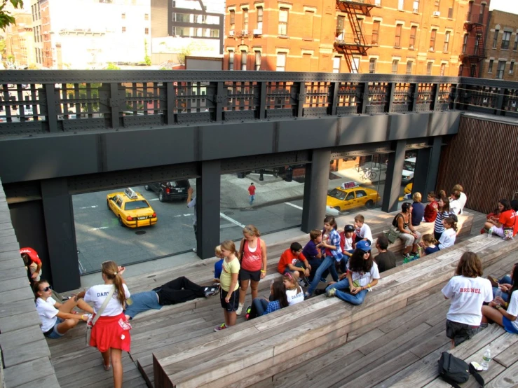 a group of people sitting on a wall next to a street