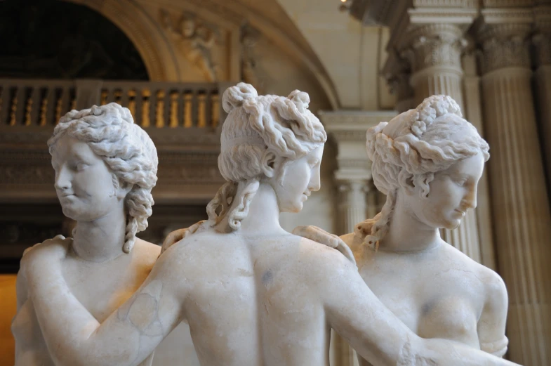 four sculptures of two women are displayed together