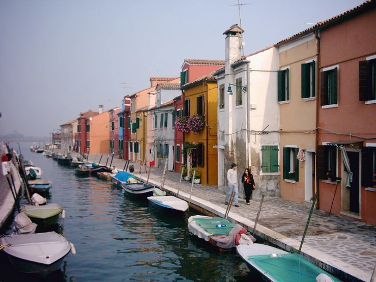 a man is walking beside the water in a row of buildings and boats