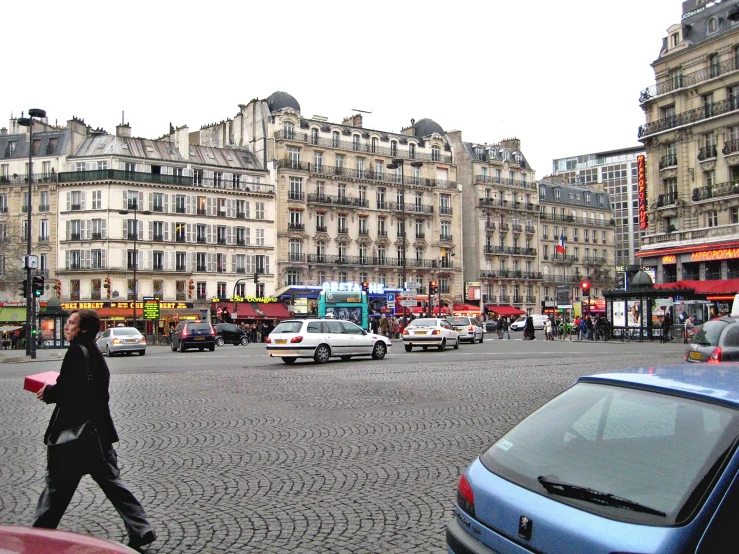 a woman crosses the road in front of a busy city street