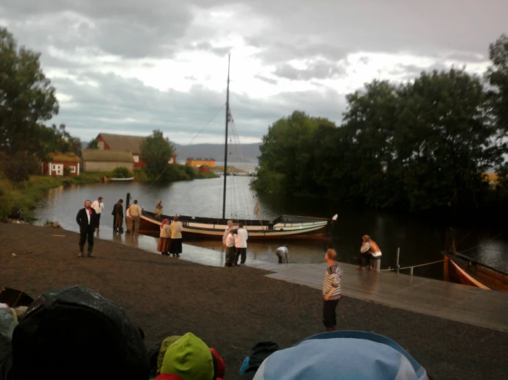 group of people standing around on dock in front of boat