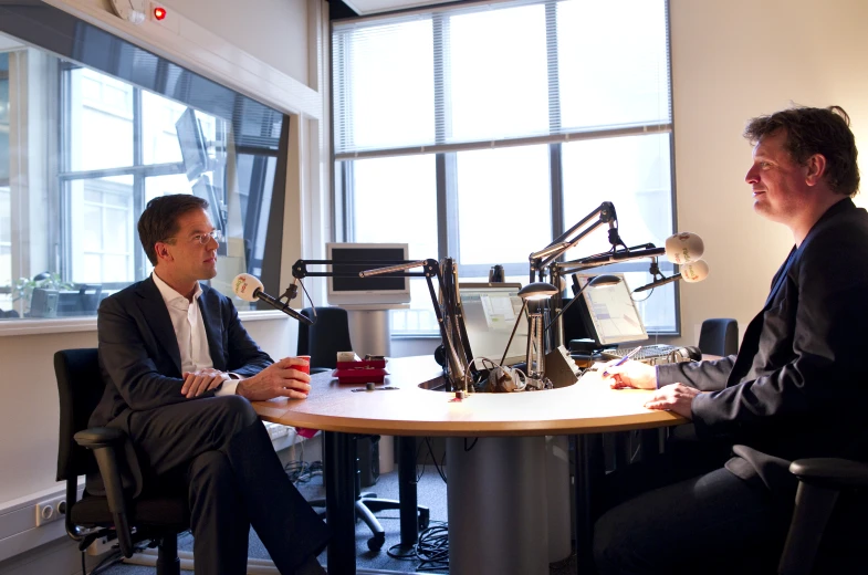 two men talking around a round table in an office