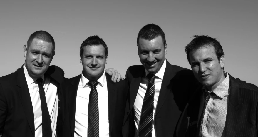 four men in suit and ties stand together