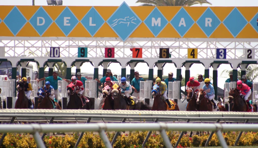 the starting gates for the race with jockeys and horses on the track