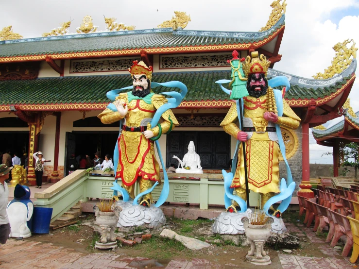 statues at an outdoor asian shrine with people standing nearby
