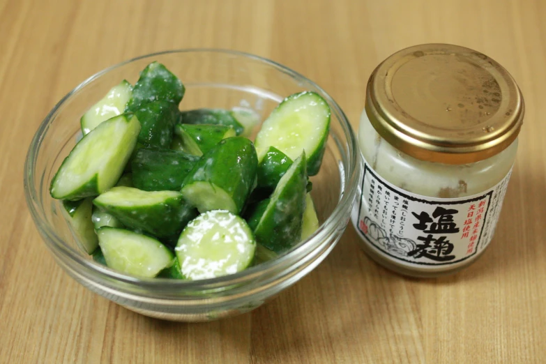 a small glass bowl filled with cucumbers next to a jar