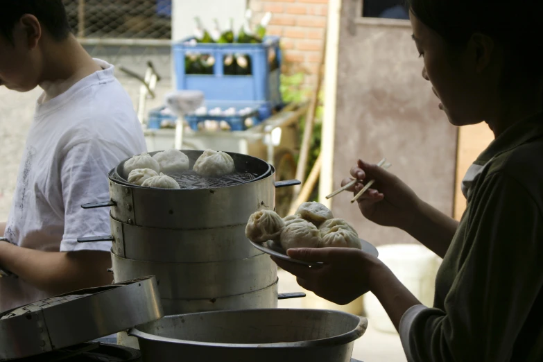 two people standing over food on an outdoor stove