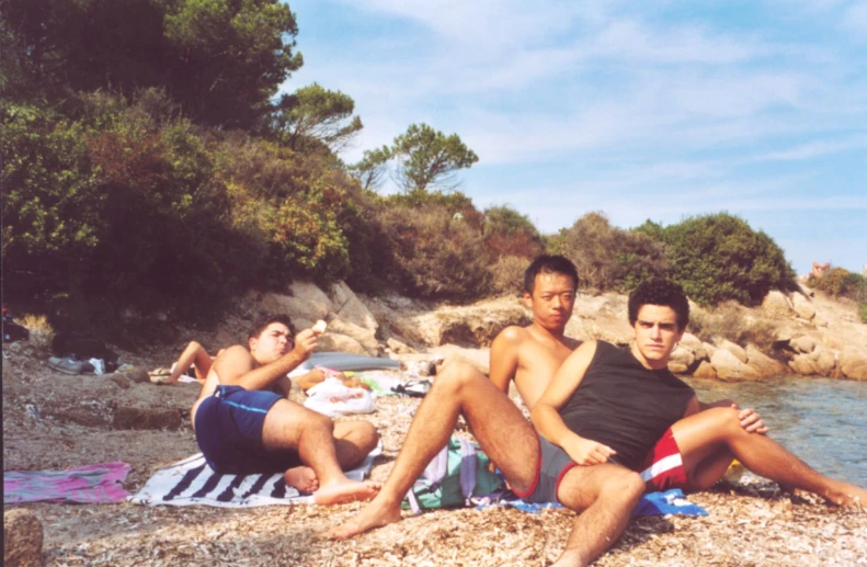 four people that are laying down on the sand