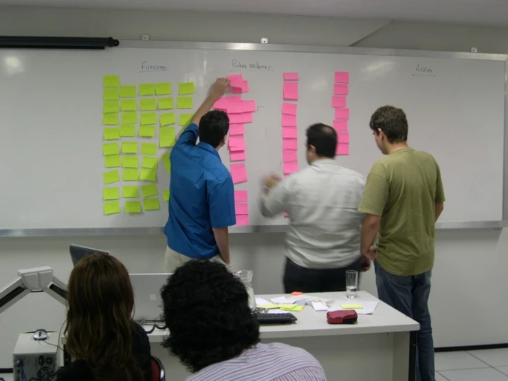 four people are writing on a board that is painted with neon colors