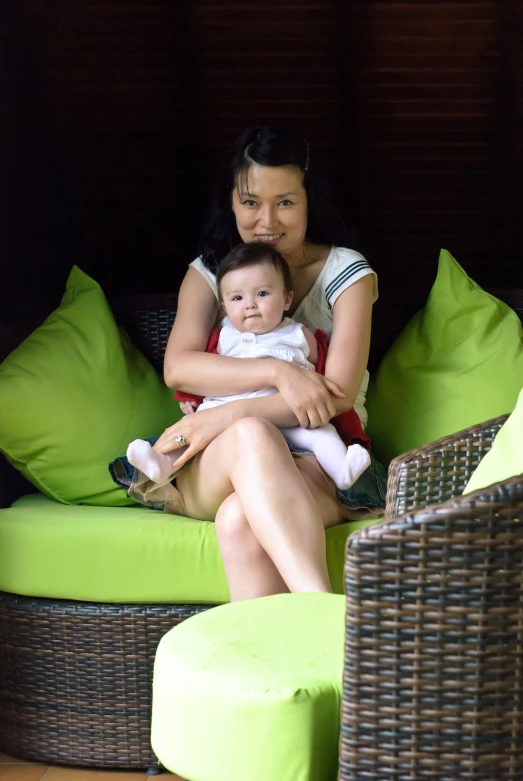 a woman sitting on top of a chair holding a baby