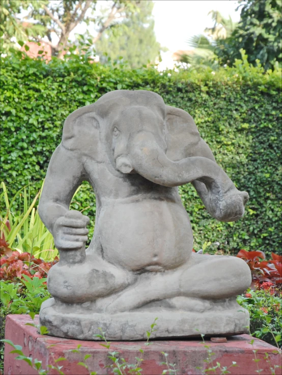 an elephant statue sitting in the middle of a garden