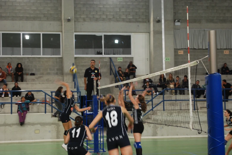 a group of girls playing a game of volleyball on a court