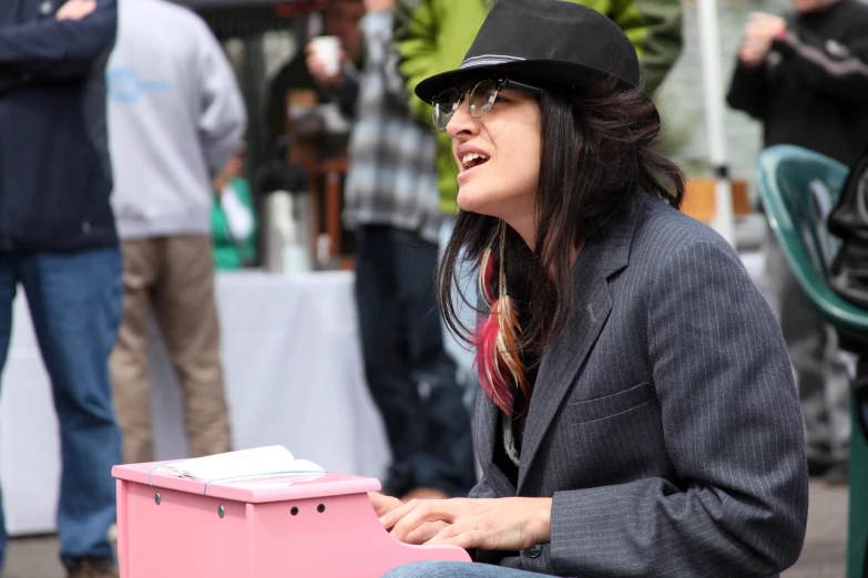 a woman in hat and glasses sitting down