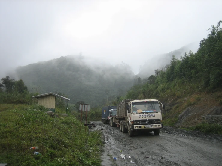 two trucks in the middle of the road with hills