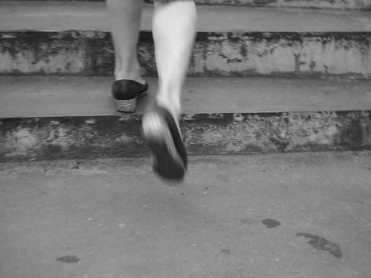 black and white pograph of a person's feet and foot stepping on a skateboard