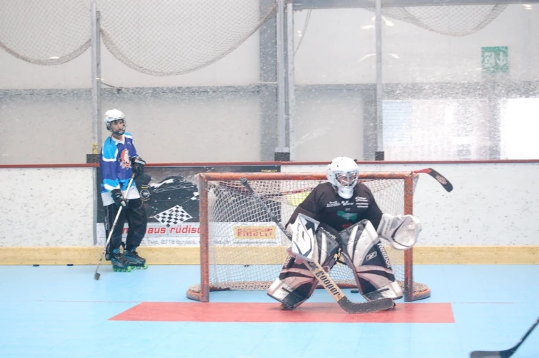 two people wearing masks and standing behind a net playing ice hockey
