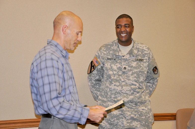 a man holding soing in his hand near a man wearing a military uniform