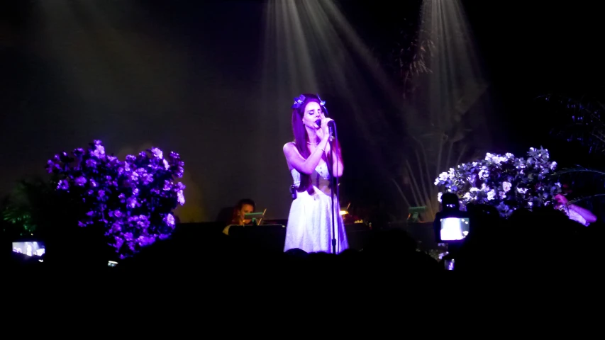 a woman in a dress holding a microphone on stage