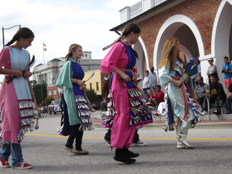 a group of people in native indian dresses walking down a street